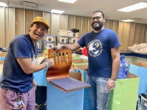 Two male students sort furniture for donation.